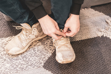 close up man put on casual sneakers and tie shoelaces on the couch and carpet b