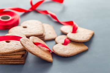 Holiday sweets. Swedish christmas gingerbread cookies pepparkakor, decorated with red ribbon, on a dark gray background, horizontal