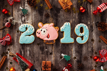 Christmas gingerbread cookies with funny pig and new 2019 year numbers at decorated xmas wooden table background.