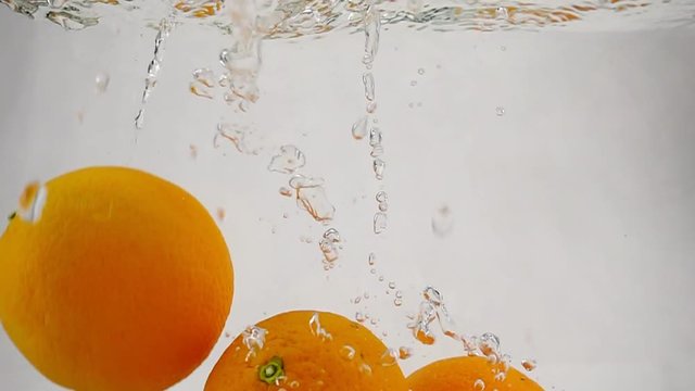 The orange falling in water with bubbles. Video in slow motion. Fruits on isolated a white background.