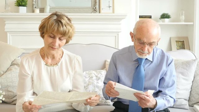 Portrait of happy attractive elderly couple watching old letters. Lovely retirement people spending time together