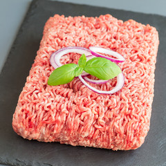 Minced meat from pork and beef. Ground meat with ingredients for cooking on a dark slate board,...
