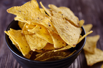 Nachos, corn chips in a black bowl  on a wooden background