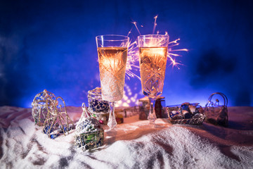 Two glasses of champagne with Christmas decoration. Traditional winter holiday alcohol drink in snow with creative New Year artwork. Copy space.
