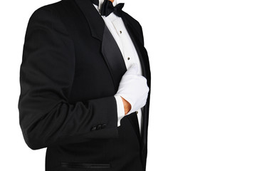 Closeup profile of a man wearing a tuxedo and white gloves holding his lapel.