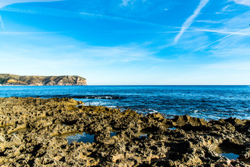 Fototapeta na wymiar Olas rompiendo contra las rocas en la orilla del mar Hermosa vista del Cabo de San Antonio en Jávea, Comunidad Valenciana, Alicante, España