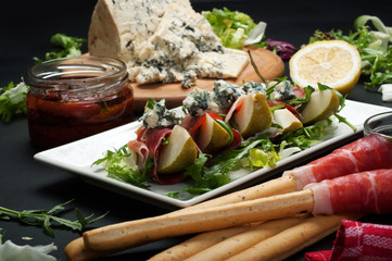 Pear with dried meat, blue cheese and a mix of salad. Macro shooting, selective sharpness. Blurred background. Mediterranean cuisine