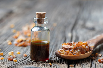 A bottle of myrrh essential oil with myrrh resin on a spoon - obrazy, fototapety, plakaty