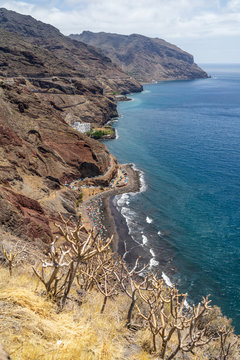 View of the beach with volcanic black sand - Playa de Las Gaviotas and the rocky shore from the observation deck Mirador Las Teresitas. Tenerife. Canary Islands. Spain.