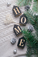 Fototapeta na wymiar Cozy Winter Concept, Pine Branches and Home Letters on Beige Knitted Background, Top View