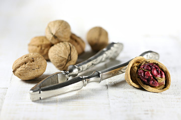Red Danube Walnuts with silver nutcracker on wooden background