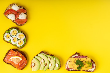 A few sendwiches on the yellow backgraund. Top view.