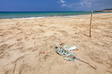 Fototapeta na wymiar Perfect empty unspoiled beach, small pile of rubbish (tangled plastic ropes) on fine sand, calm sea in background. Ocean littering concept. Karpass, Northern Cyprus