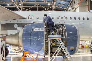Mechanic specialist repairs the maintenance of engine of a passenger aircraft in a hangar
