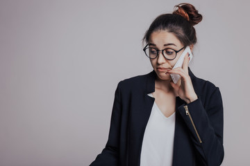 I am a little disappointed in you after hearing. The girl looks frustrated or confused when talking on the phone. Woman with mobile phone, in glasses and with hairstyle top knot