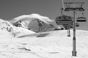 Ski-lift and ski slope in snowy mountains at sunny winter day