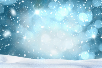Falling snow with white snow on the ground at night and freezing blue tone bokeh of lights in background. Copy space.