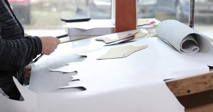 Shoemaker master cutting shoe leather as template, clicking the upper in a shoes factory.4k