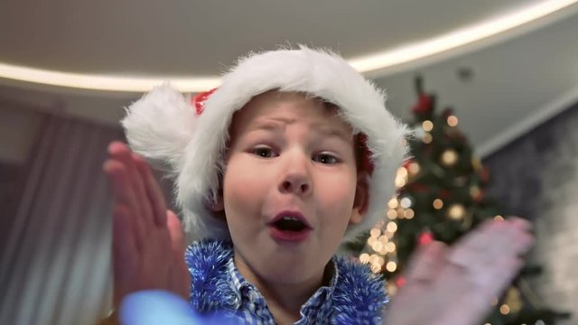 Close-up face of astonished little cute boy opening gift box smiling and clapping hands