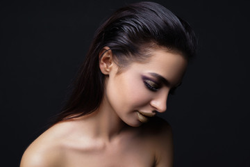 Fototapeta premium Fashion young clean skin Woman face portrait close up on black background. Model girl with holiday golden Glamour shiny professional makeup. Beauty gold metallic 