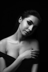 Naklejka premium Sexy młoda kobieta czarno-biały portret na czarnym tle. Uwodzicielska młoda kobieta w bieliźnie w ciemności. Seksowny dama z długimi włosami pozowanie w świetle reflektorów