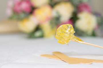sugar paste or wax honey for hair removing with wooden waxing spatula sticks. flower background - depilation and beauty concept
