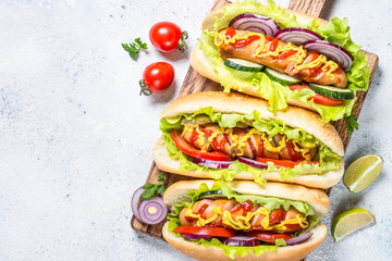 Hot dog with fresh vegetables on white top view.