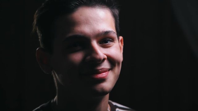portrait of awesome young man in dark room. Smiley face looking at camera, closeup