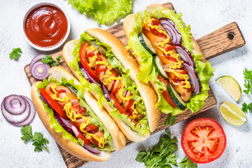 Hot dog with fresh vegetables on white top view.