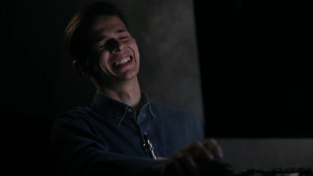 young laughing man vaping in front of computer at home in dark room
