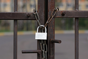 Gate is locked with padlock. Rusted lock on a metal chain.  Entrance to prison.