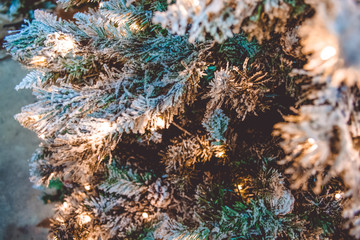 Fototapeta na wymiar Christmas tree with fake snow and garland lights. Close up.