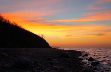 Sonnenuntergang am Strand mit Wellen und Sand an der Ostsee nahe Warnemünde im Urlaub