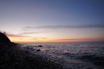 Sonnenuntergang am Strand mit Wellen und Sand an der Ostsee nahe Warnemünde im Urlaub