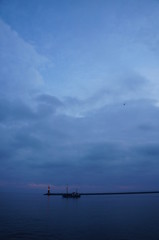 Fototapeta na wymiar Leuchtturm und Hafeneinfahrt mit Schiffen und Fischerkutter in Warnemünde an der Ostsee im Hafen am Meer