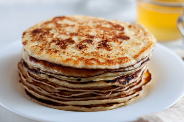 On the table there is a dish with pancakes and honey