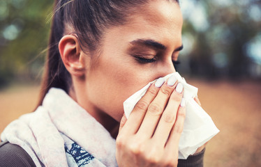 Cold and flu. Woman blowing her nose with a tissue