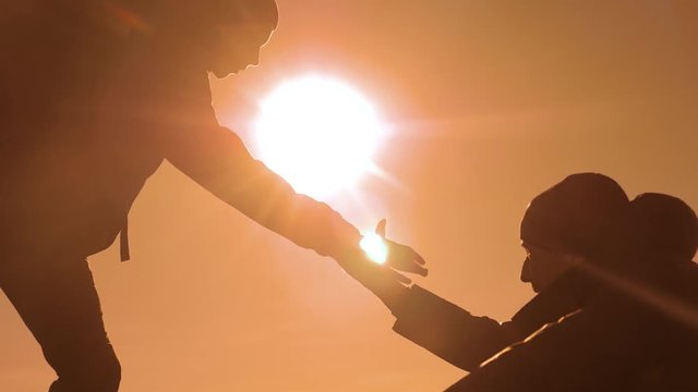 teamwork tourists business travel trip lends a helping hand. two men with backpacks hiking help each other silhouette in mountains with sunlight. slow motion video. teamwork friendship hiking help