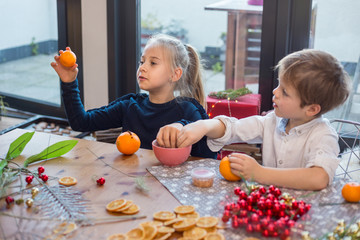 Siblings prepairing orange pomander for Christmas season.  Simple idea for kid friendly festive...