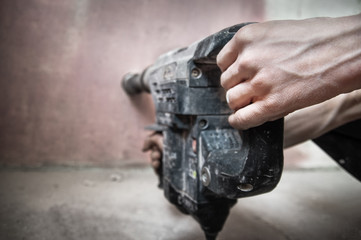 The builder works as a puncher, drills a wall, repairs indoors