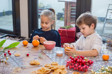 Siblings prepairing orange pomander for Christmas season.  Simple idea for kid friendly festive...