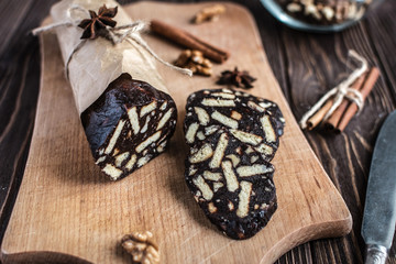 Chocolate sachocolate; sausage; background; wooden; baked; biscuit; board; breakfast; brown; butteusage on a wooden background. Dessert made of biscuits, chocolate and nuts is sliced on a wooden board
