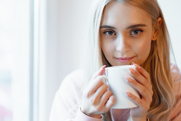 An elf alike, young girl enjoying a cup of coffee or milk while
