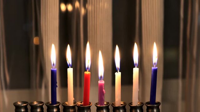 Seven candles in hanukkiah are burning on the sixth day of the Jewish holiday Hanukkah on light curtain background. 4k