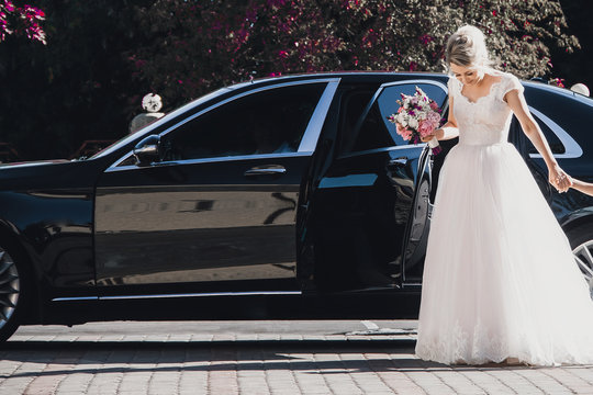 Happy bride and groom in a black car on wedding day