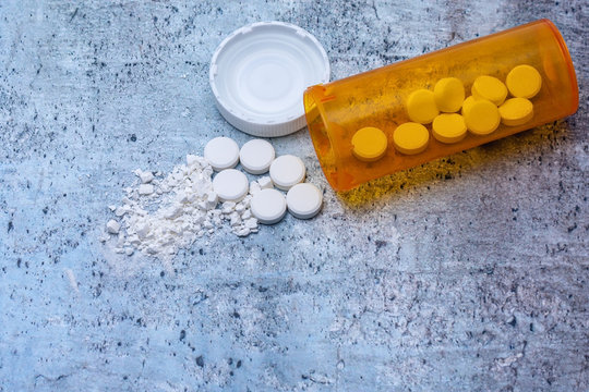 Opioid and drug addiction epidemic concept in America with pills, cap, and bottle and room for copy text
