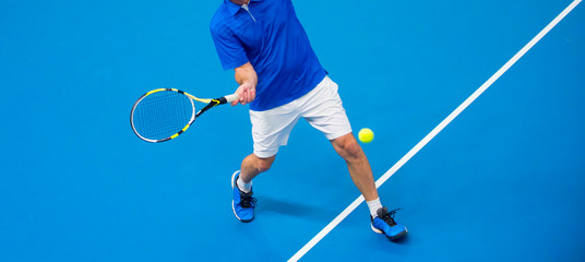 man playing tennis on blue floor