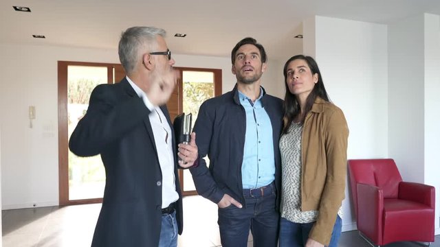 Real estate agent showing modern house to potential buyer couple