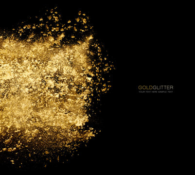 Golden glitter powder scattered in black . Gold dust explosion
