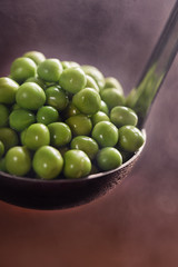 Young green peas with steam on a ladle.Tasty and healthy food.
